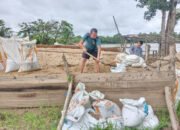 Satgas TMMD Kodim 1012/Buntok Mengisi Karung Pasir untuk Diangkut Menggunakan Perahu
